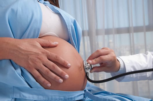Doctor examining a pregnant woman with a stethoscope