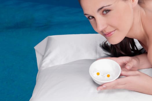 Woman holding a bowl of flowers on a massage table