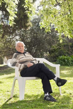 Portrait of a man sitting on a chair in a park