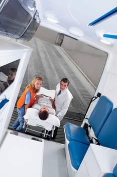 Paramedics leading a patient on a gurney into an ambulance