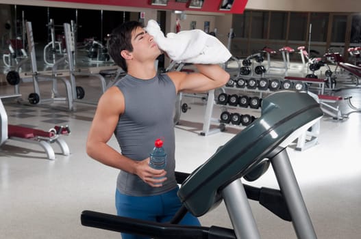 Man wiping his face with a towel on a treadmill