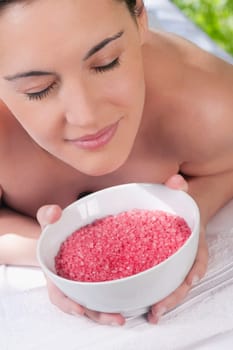 Close_up of a woman lying on a massage table and smelling a bowl of bath salt