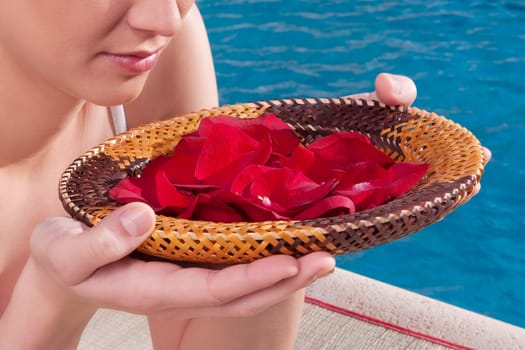 Woman holding a plate of rose petals at the poolside