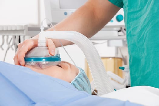Anesthetist using an oxygen mask on a patient in a hospital