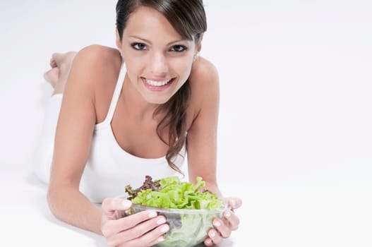 Woman lying with a bowl of salad in her hands