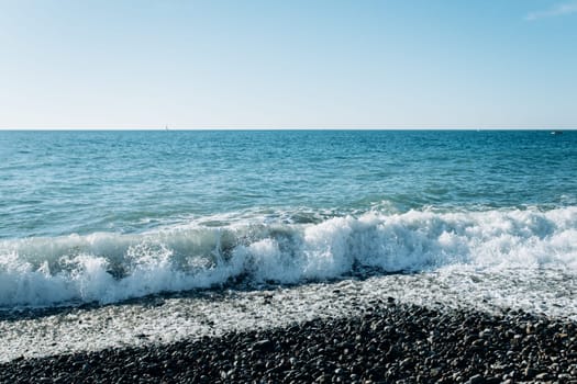 Stones on the beach. The waves of the sea beat against the rocks on the shore. Beautiful view of the sea.