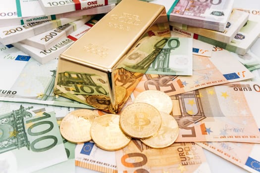Bitcoin BTC Gold coins with bills of euro banknotes and gold bullion. Bitcoin and gold lie on Euro banknotes