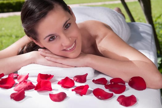 Portrait of a woman lying on a massage table with rose petals
