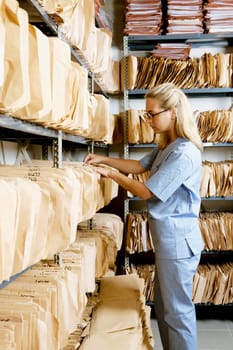 Female doctor checking records in a record room