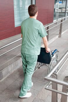 Male nurse carrying a wheelchair