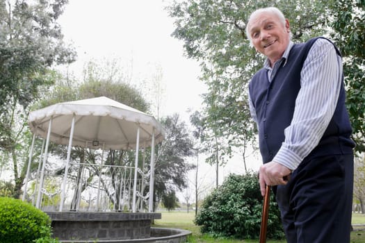 Portrait of a man standing in a garden with a cane
