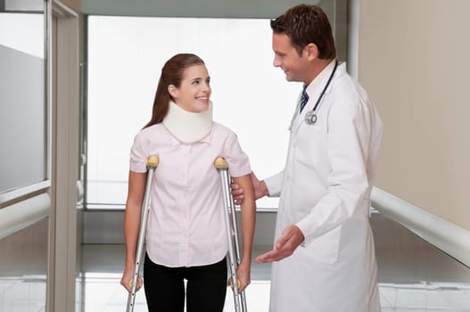 Doctor assisting a patient to walk in a hospital corridor
