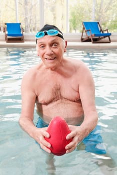Portrait of a man playing with a rugby ball in a swimming pool
