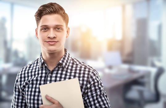 Young man holding a file in a modern office