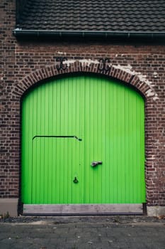 Large bright green wooden doors in an old brick building. Doors in a renovated building.