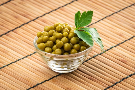 Canned green peas in the bowl on wood background