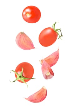 Isolated vegetables. Mixed tomatoes and garlic falling down isolate on white with clipping path as package design element. Full depth of field. Food levitation concept.
