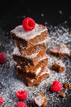 Homemade vegan chocolate brownies with nuts, lemon icing and raspberries