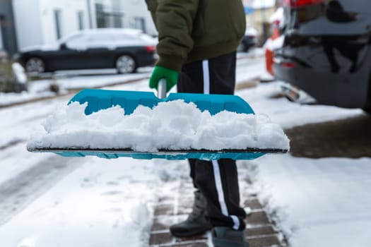 Child shoveling and removing snow in front of his house in the suburb