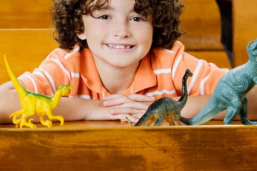 Schoolboy sitting with toys in a classroom