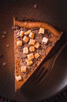 Chocolate cheesecake with salted caramel on dark background