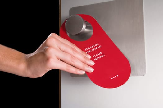 Close_up of a personŽs hand hanging do not disturb sign on a door handle