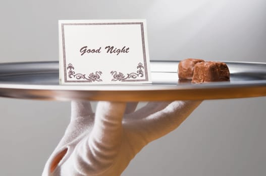 Close_up of a personŽs hand carrying sweet food and good night note in a plate