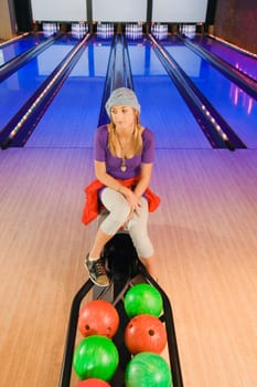 Teenage girl sitting in a bowling alley and thinking