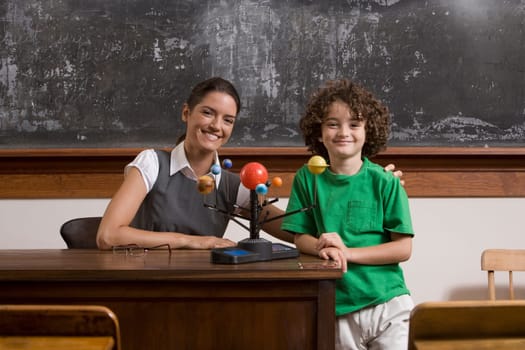 Schoolboy and his teacher with model of solar system in a classroom