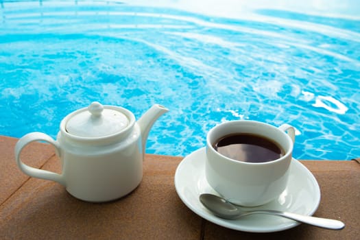 cup on the table near the pool . White ceramic coffee cup