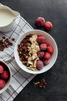 Frozen strawberry with granola, almond flakes, cream on concrete table. High quality photo