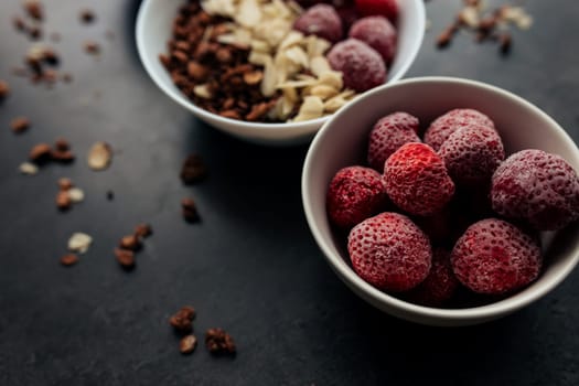 Frozen strawberry with granola, almond flakes on concrete table. High quality photo