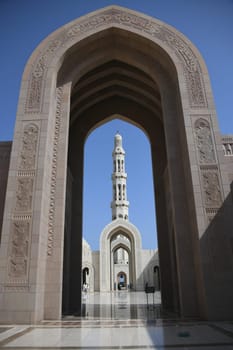Archway with the Arabic inscription Great Sultan Qaboos Mosque and the main minaret in a visual axis. It is considered to be one of the most important buildings in the Sultanate of Oman.