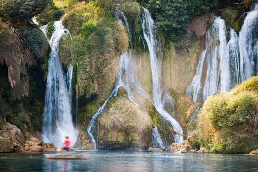 Kravice Waterfalls, Bosnia and Herzegovina, Europe. Summer travel. Tourist in boat at foot of waterfall.
