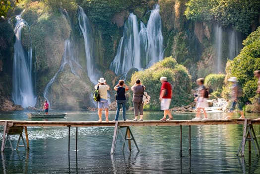 KRAVICE WATERFALLS, BOSNIA AND HERZEGOVINA - SEPTEMBER 10, 2015: People on bridge taking pictures of waterfalls. Bosnia and Herzegovina, Europe.