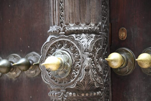 The famous and historic Indian style front doors adorn many houses in Stone Town on the island of Zanzibar. The Indian doors have a domed frame and brass tips.
