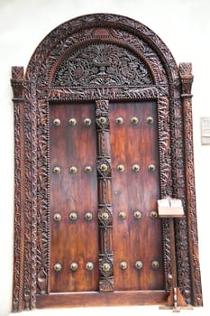 The famous and historic Indian style front doors adorn many houses in Stone Town on the island of Zanzibar. The Indian doors have a domed frame and brass tips.