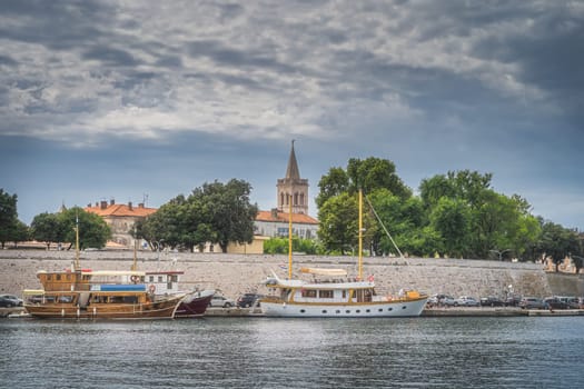 Marina with moored sailboats in Zadar bay. Fortification, walled old town and belltower of Church of St. Donata in background, Croatia