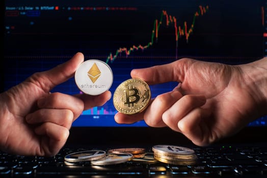 Business men holding bitcoin and ethereum coin whit computer trading chart background. Bitcoin and altcoin the most important cryptocurrency concept