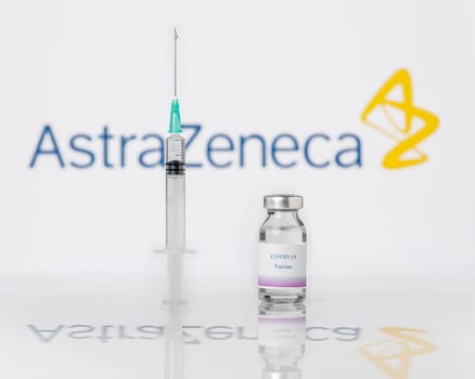 Teo, Spain  January 25, 2021: AstraZeneca Covid-19 vaccine concept. A syringe and a vial over the AstraZeneca company logo blurred in the background.