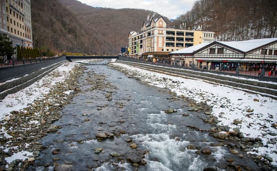 Sochi  Russia - January 02  2021: The Mzymta river in the Krasnaya Polyana resort. Tourists walk along the embankment