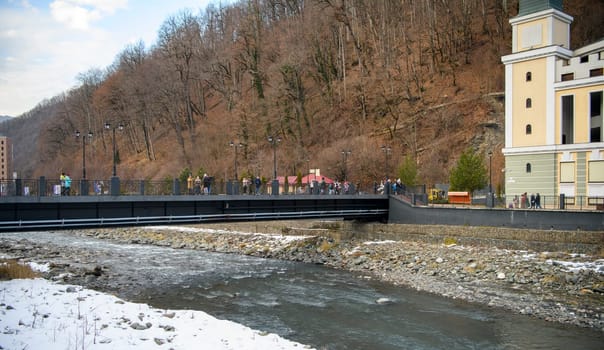 Sochi  Russia - January 02  2021: The Mzymta river in the Krasnaya Polyana resort. Tourists walk along the embankment