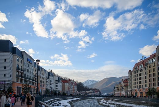 Sochi  Russia - January 02  2021: The Mzymta river in the Krasnaya Polyana resort. Tourists walk along the embankment