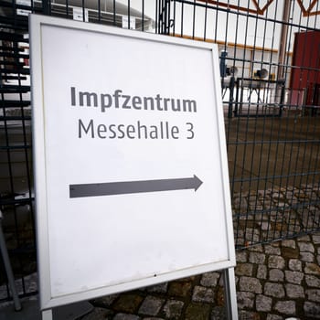 Directional arrow to a vaccination center on the outskirts of the city of Magdeburg in Germany. Sign with the inscription vaccination center (Impfzentrum) in exhibition hall 3