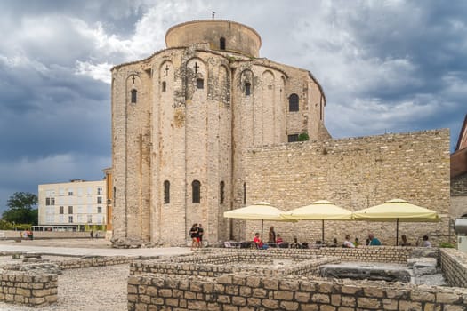 Zadar, Croatia, July 2019 Tourists relaxing in shade of St. Donata, circular church in early Romanesque architecture style