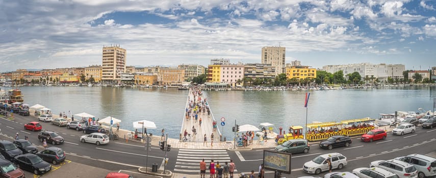 Zadar, Croatia, July 2019 Panoramic view on pedestrians crossing famous bridge, Gradski most, with marina and residential district in the background
