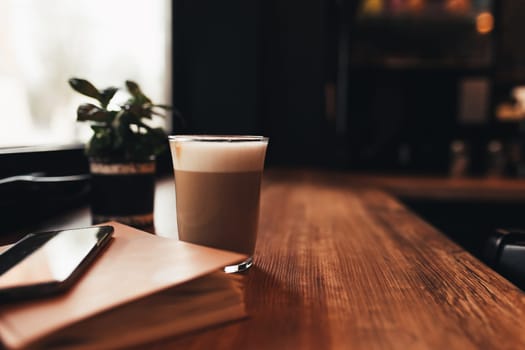 Cup of coffee, notebook, phone at table in cafe. Blurred background. High quality photo