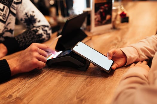 Cashless payment with NFC and phone in a cafe terminal. Blurred background. High quality photo