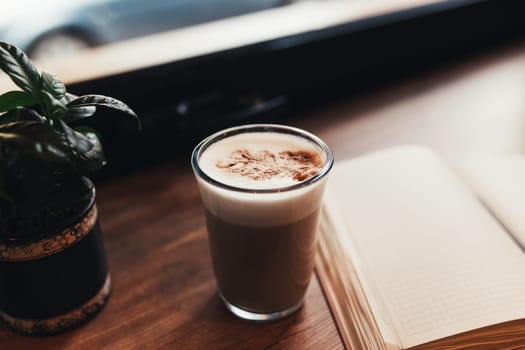 Cup of coffee, notebook at table in cafe. Blurred background. High quality photo