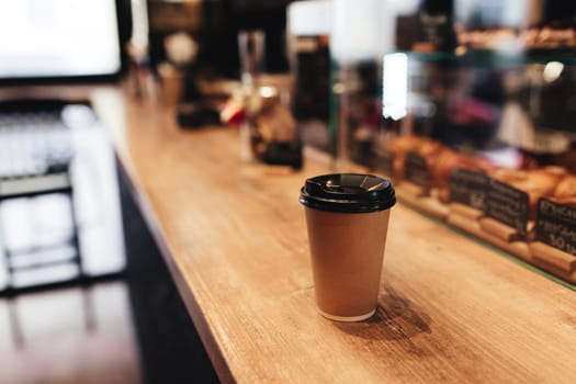 Paper coffee cup on bar counter in cafe. Blurred background. High quality photo